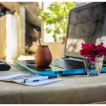 A Laptop Placed On a Table Alongside a Notebook And a Pen. Side Hustle