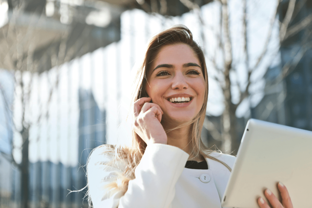 A Woman Holding a Laptop While Talking On the Phone.