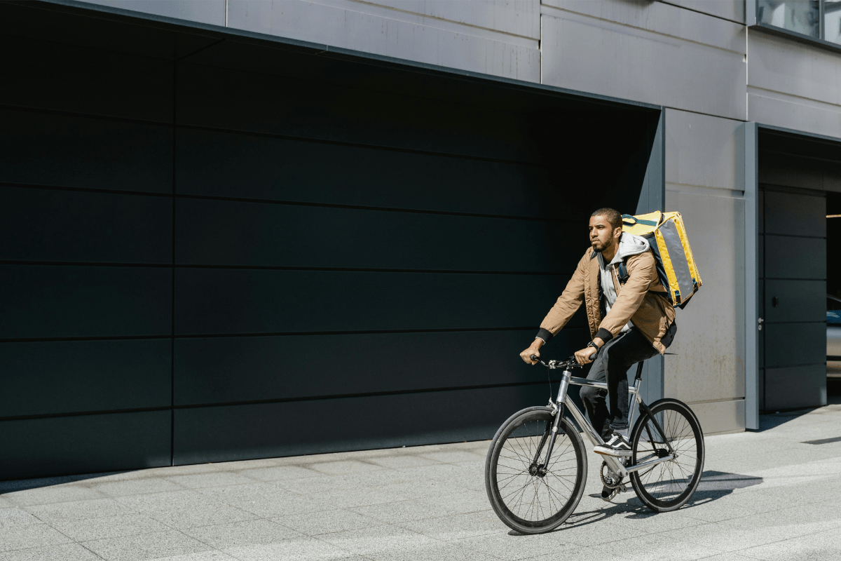 A Student Riding a Bicycle with a Food Box on their Back Illustrating Best Side Hustles for College Students