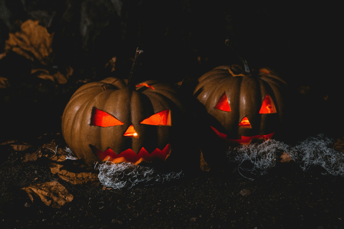 Two large carved Halloween pumpkins lit up in the dark -showcasing creative designs for selling Halloween wallpaper to make money online.