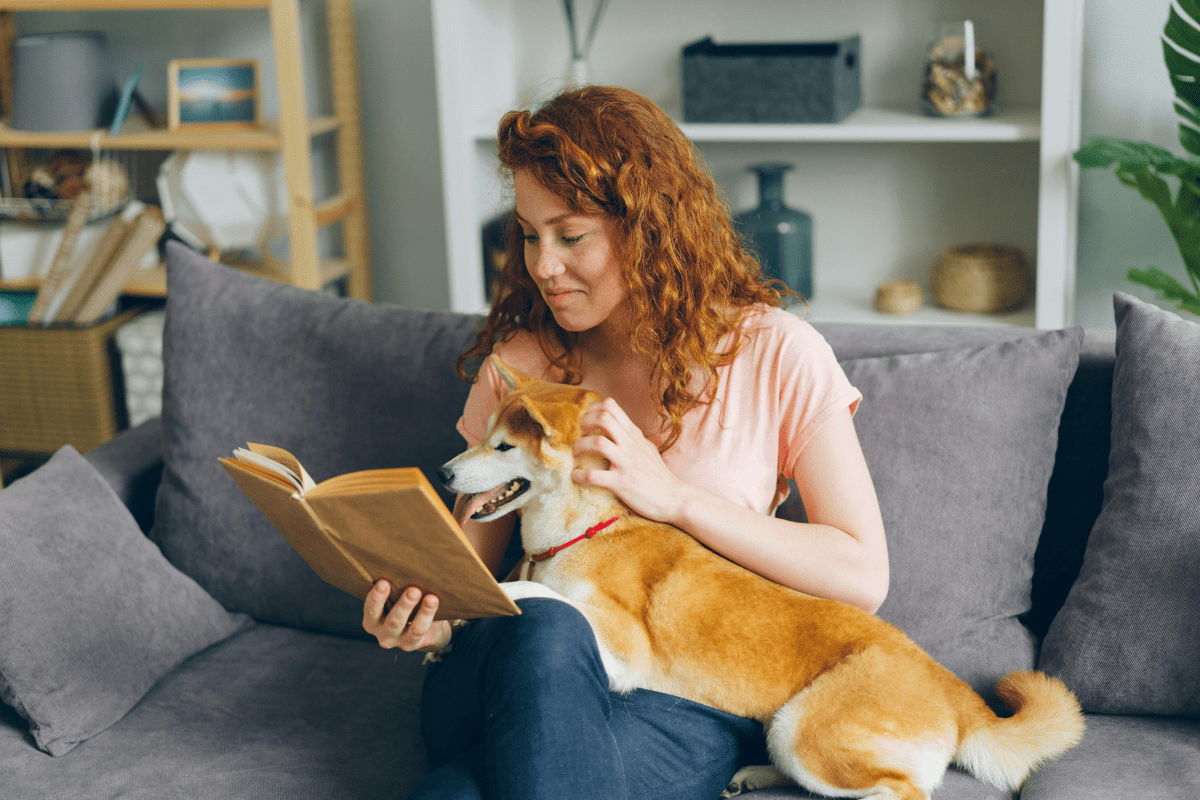 A College Student Sitting on a Sofa With a Dog Illustrating One of the Best Side Hustles for College  Students.