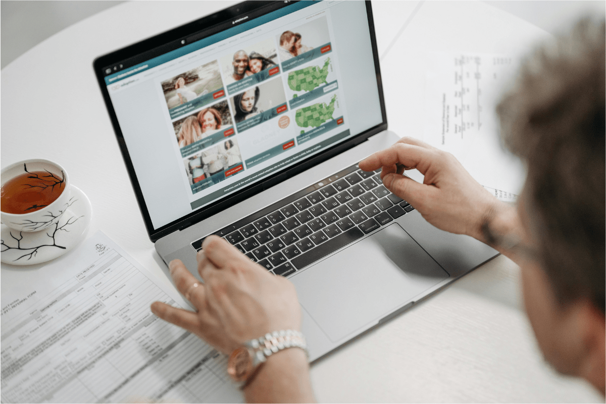 A Mans Hand Visible On Laptop Keyboard with The Screen Displaying Some Products Illustrating Side Hustles for College Students to Make Money By Selling Digital Products