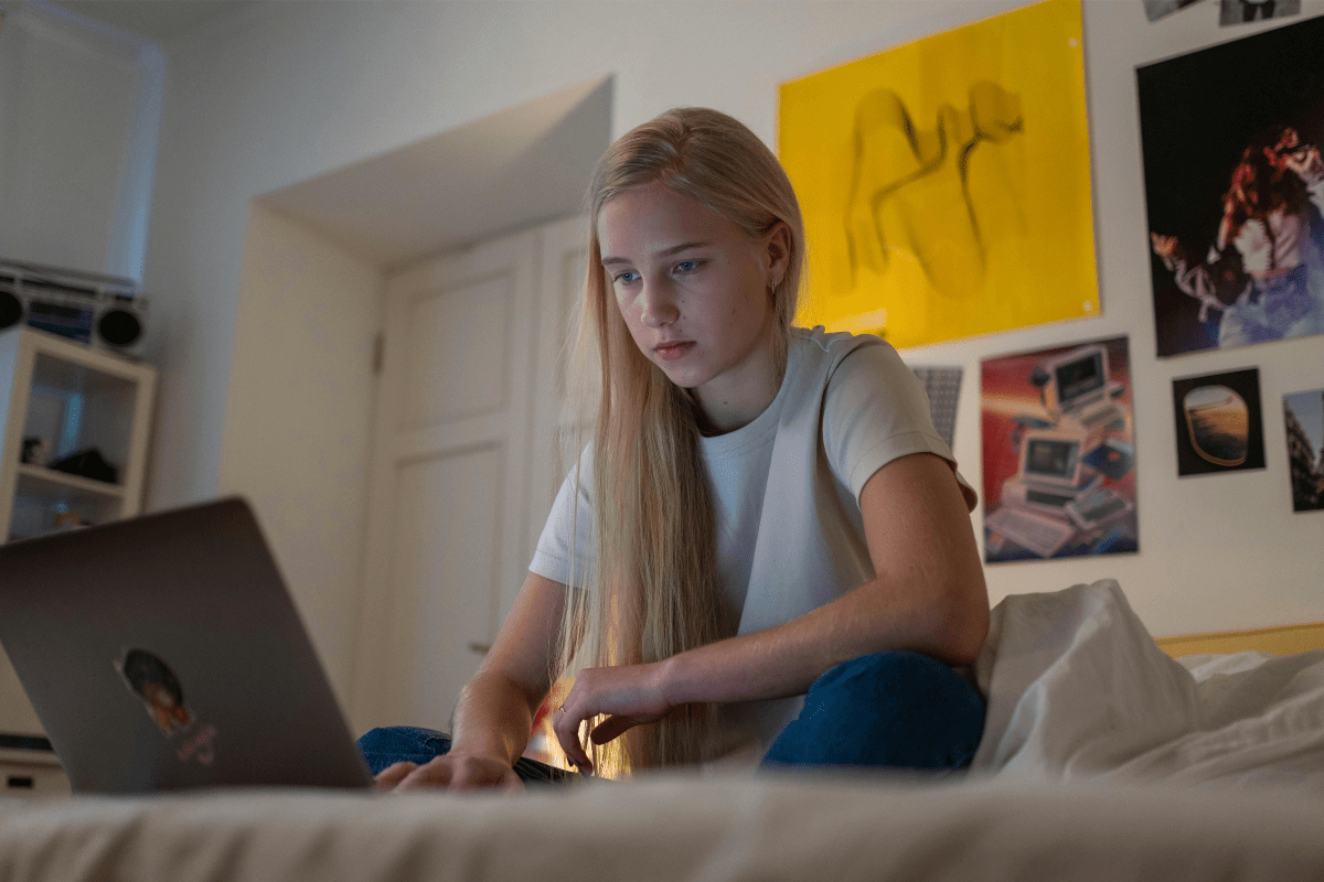 A Teenage Girl Sitting on Bed with an Open Laptop in Front Illustrating How to Make Money as a Kid