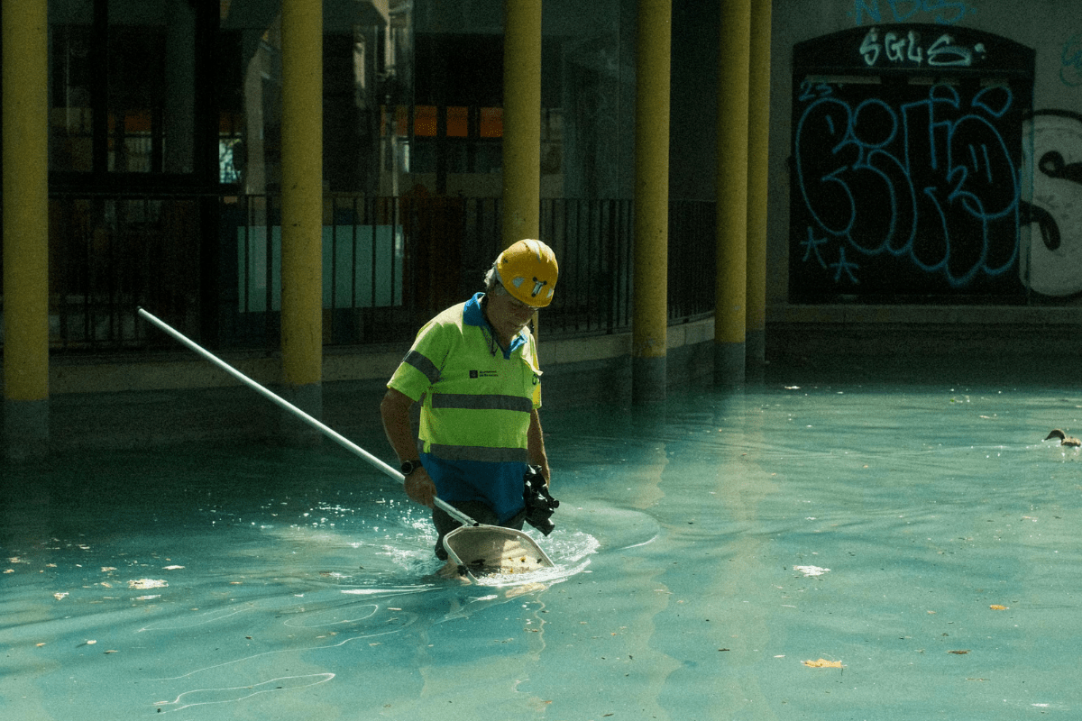 Get Training and Certifications to Become a CPO - How to Start a Swimming Pool Cleaning Business A Worker is Standing Inside the Pool Cleaning it with a Net Illustrating How to Start a Swimming Pool Cleaning Business