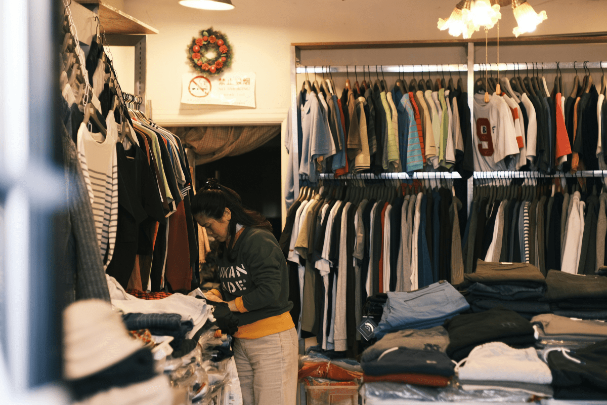 Checking Items to Ship - How to Start a print-on-demand Business A Woman Can Be Seen in a Room Filled with T-shirts and Hoodies Checking Items to Ship Illustrating How to Start a print-on-demand Business