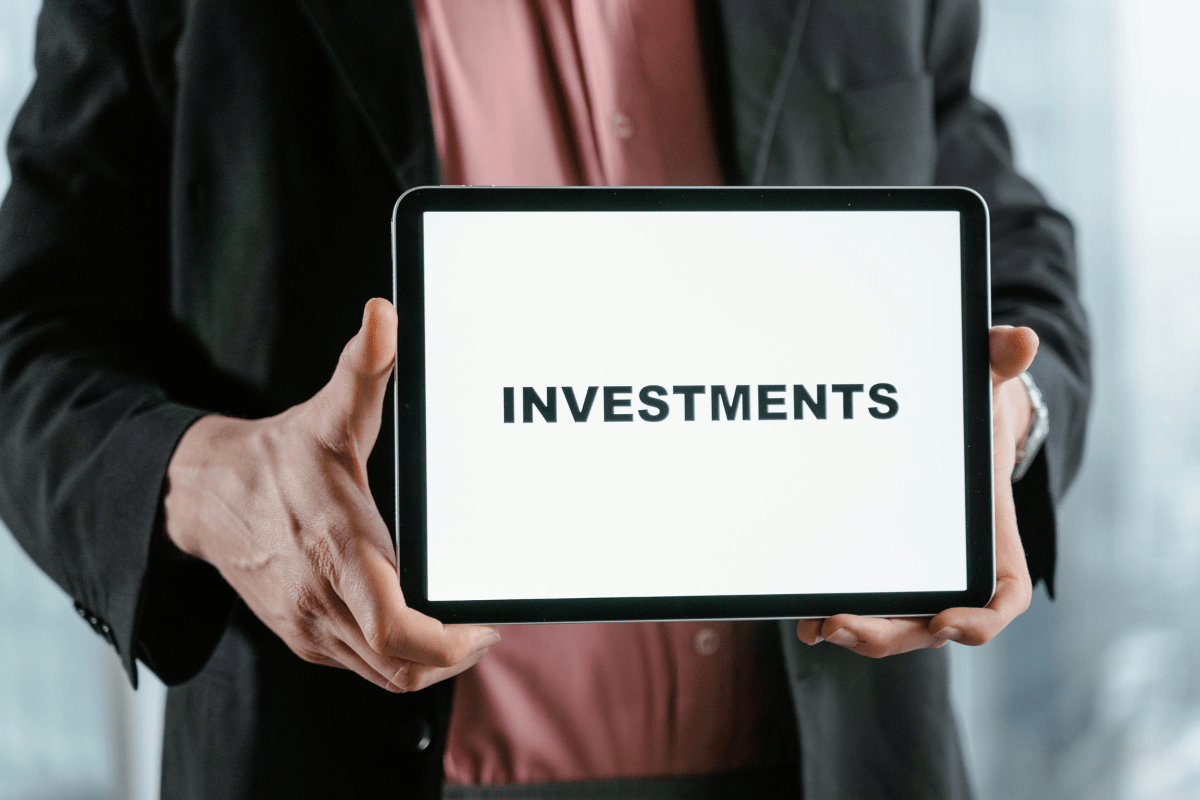 High Paying Stocks - Best Dividend Stocks for Passive Income A Person Holding a Tablet with its Screen Displaying the Word Investments Illustrating Best Dividend Stocks for Passive Income.