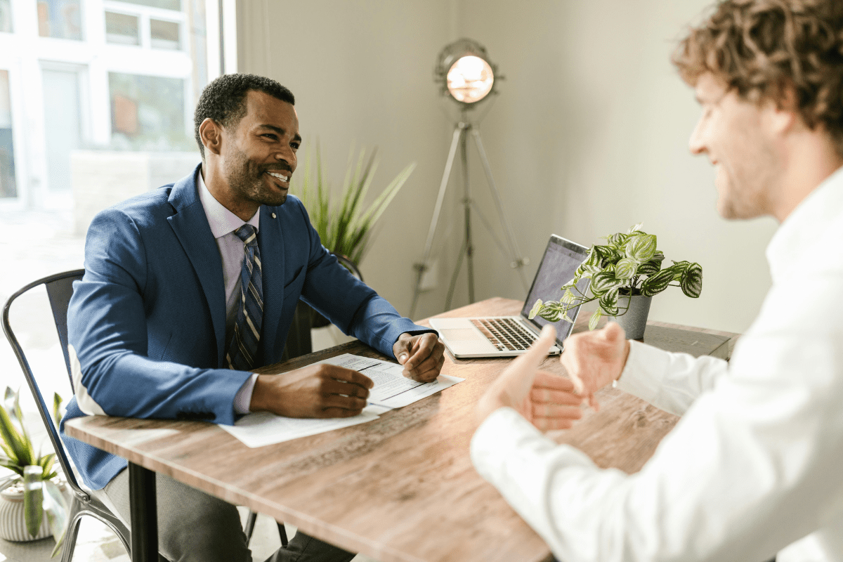 Tips to Invest - Best Dividend Stocks for Passive Income A Person Sitting across a Table with his Broker while the Broker Guides Him About Best Stocks to Invest In Illustrating Best Dividend Stocks for Passive Income