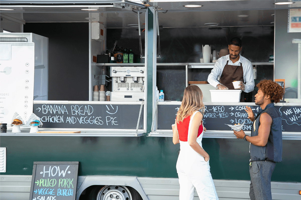 A Person Serving Two People on a Food Truck Illustrating How to Start a Food Truck Business