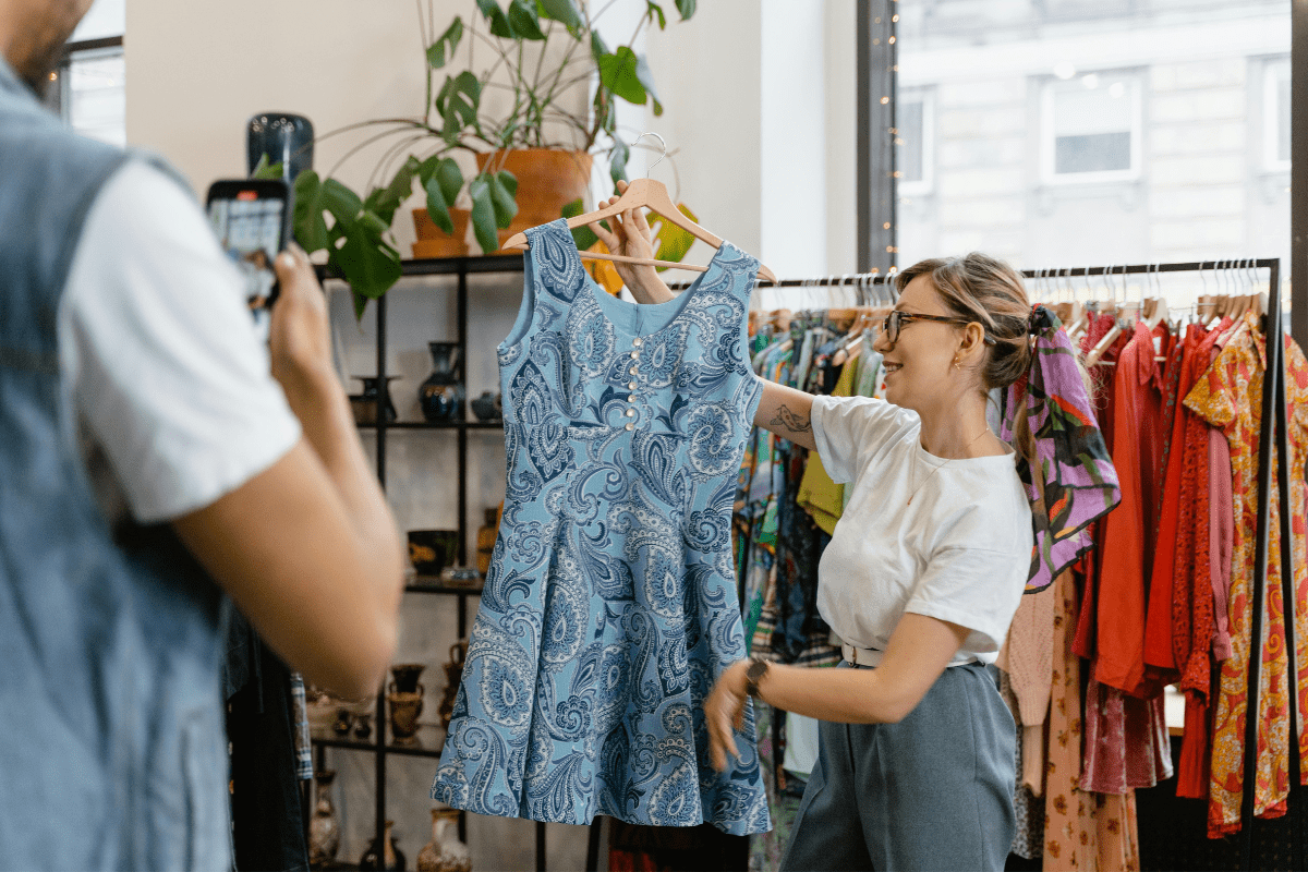 A Woman Holding a Dress While Being Photographed by a Man To Sell Clothes Illustrating Side Hustles That Pay Daily