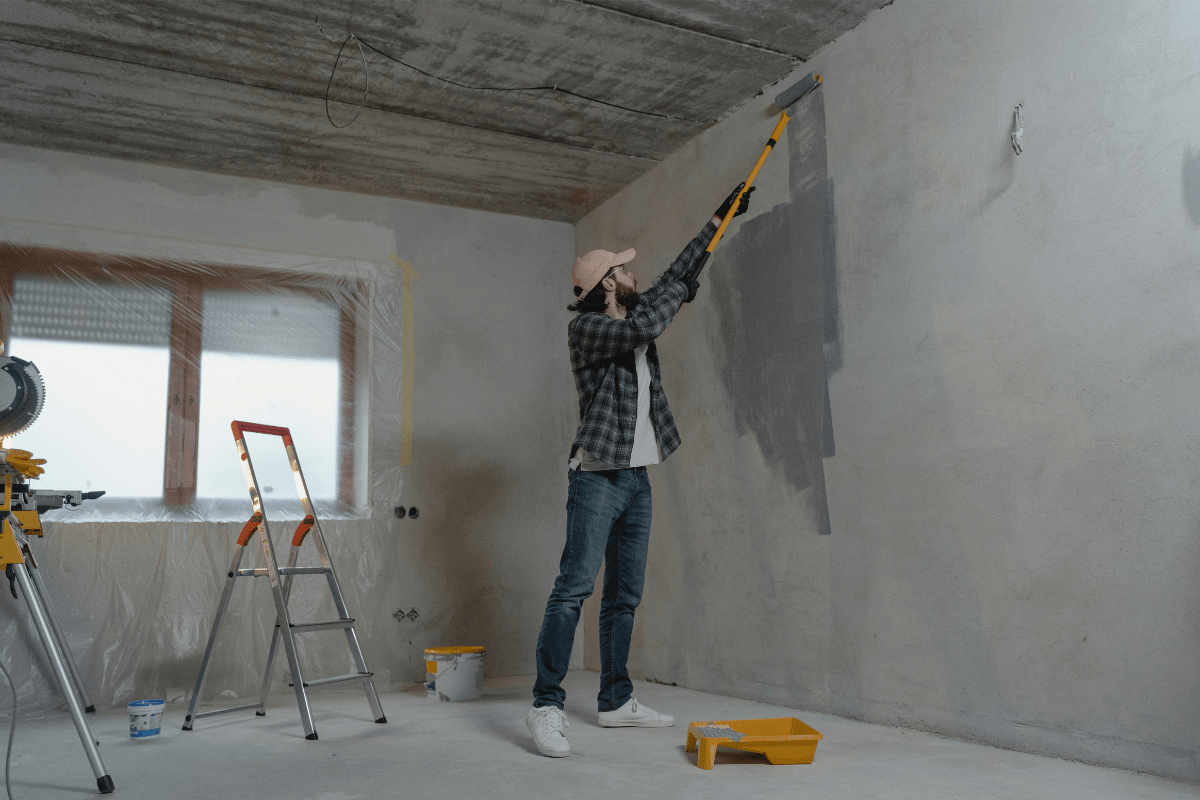 A Man Can be Seen Painting a Wall Illustrating Handyman Side Hustle