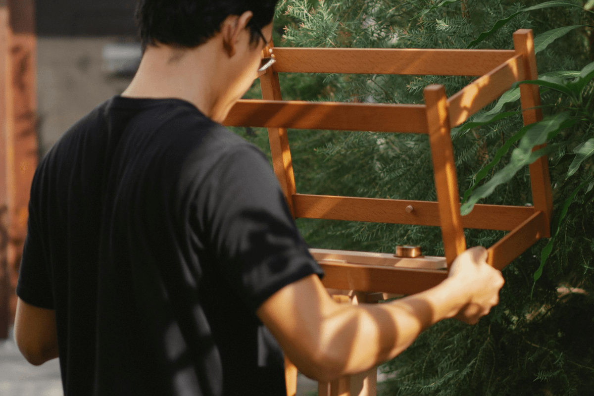 A Man Can Be Seen Holding a Furniture Piece in a Garden Illustrating Handyman Side Hustle