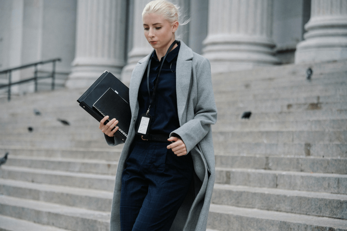 A Lawyer Can be Seen Exiting a Building Holding her Files and Tab Illustrating Side Hustles for Lawyers