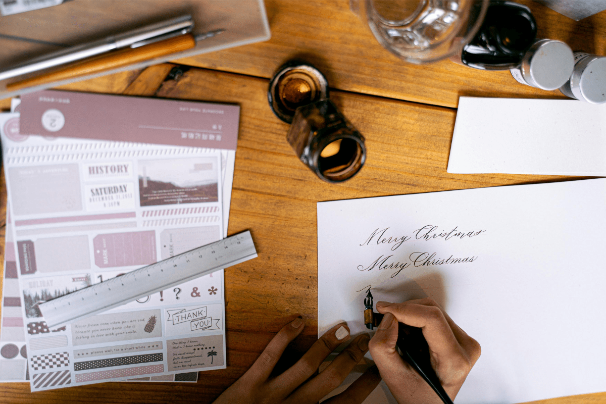 A Person's Hand Can be Seen Writing Something on Envelope Illustrating Envelope Writing Side Hustle.