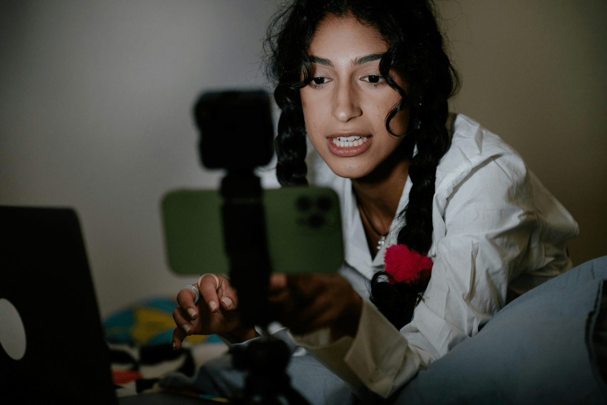 A Woman Filming Herself on an iPhone Set Against a Tripod Illustrating How to Make Passive Income on YouTube