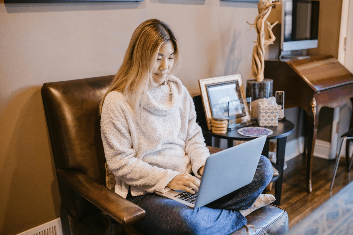 A young Woman Is Sitting on  a Couch Creating some Digital Products on Her Laptop Illustrating How to Make Passive Income on YouTube