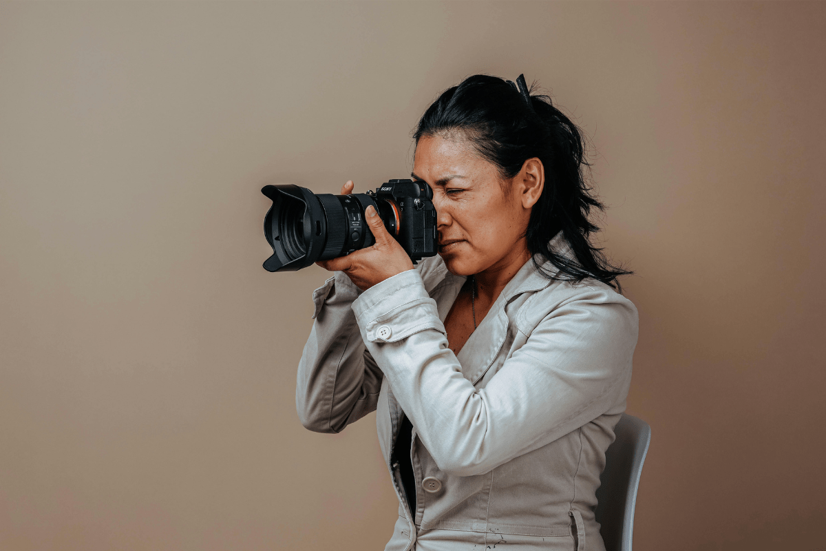 A Woman Holding a Camera Photographing Something Illustrating How to Start a Photography Business