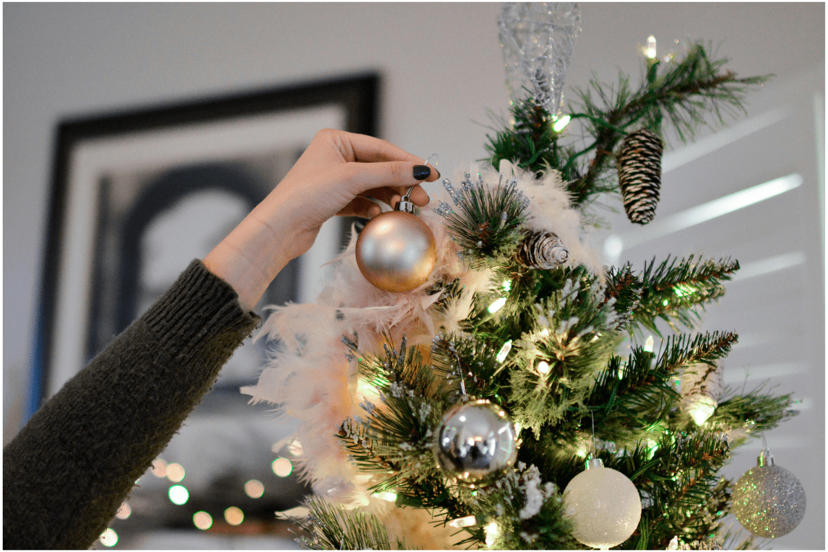 Christmas Decorations - Side Hustles for Christmas A Woman's Hand is Visible Hanging an Ornament on Christmas Tree Illustrating Side Hustles for Christmas