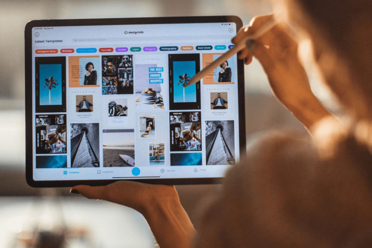 Graphic Designing - Remote Side Hustles A Woman Holding Her Tablet and Pencil Displaying Different Design Pictures on the Screen Illustrating Remote Side Hustles