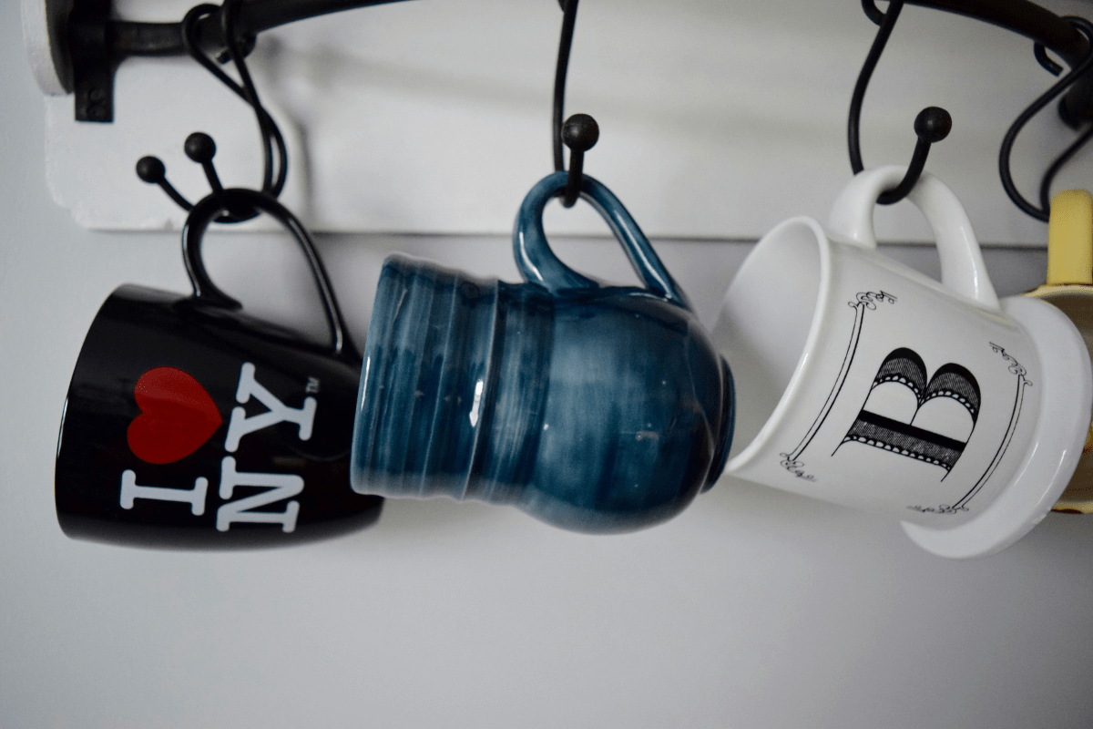 Coffee Mugs - Best Things to Sell on Etsy to Make Money Coffee Mugs Hanging from Hooks Against a Wall Illustrating Best Things to Sell on Etsy to Make Money