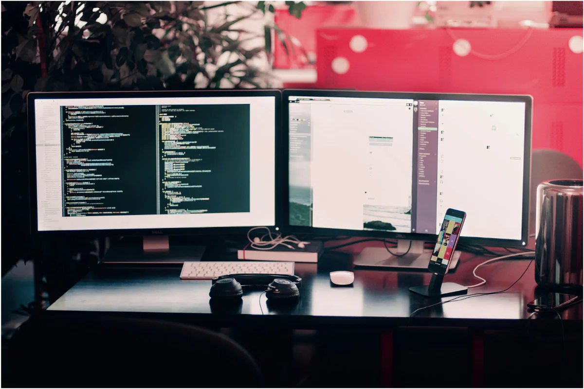 Two Computer LED's Placed on a Table Displaying Coding etc. Illustrating Remote Side Hustles.