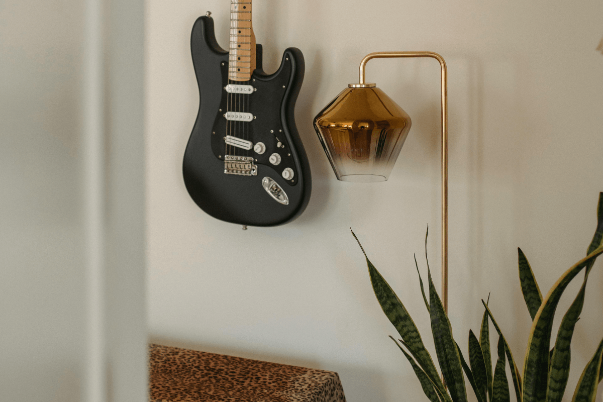 A Metal Lamp With a Guitar Hanging Against a Wall Can Be Seen Illustrating Welding Side Hustle Ideas