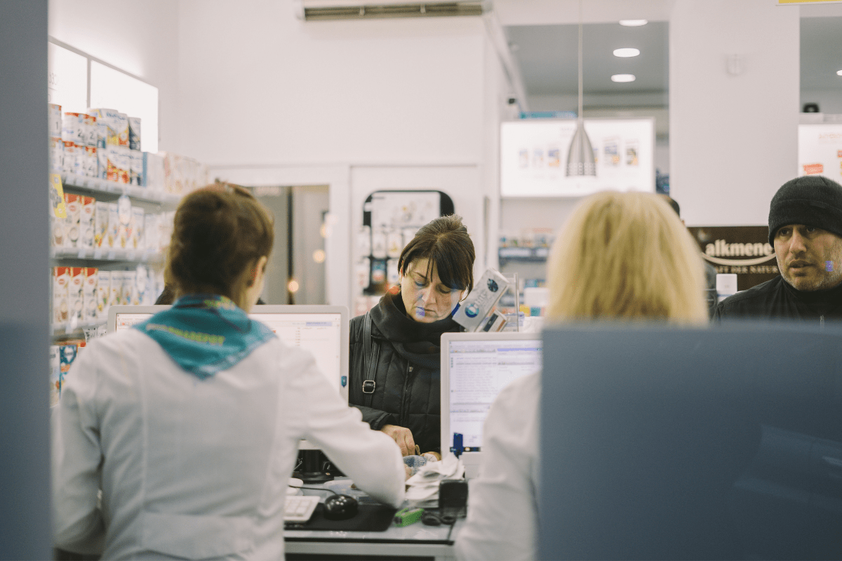 A Pharmacist Dealing With Two Customers Illustrating Pharmacist Side Hustle Ideas.