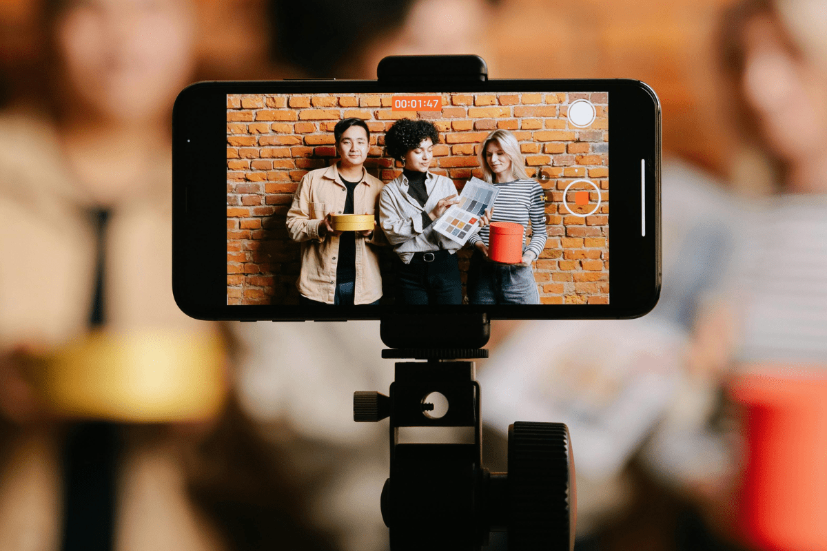 Content Creation - Side Hustle Apps Mobile Phone Screen Can be Seen Set on a Tripod Where Three Person Can be Seen Illustrating Side Hustle Apps