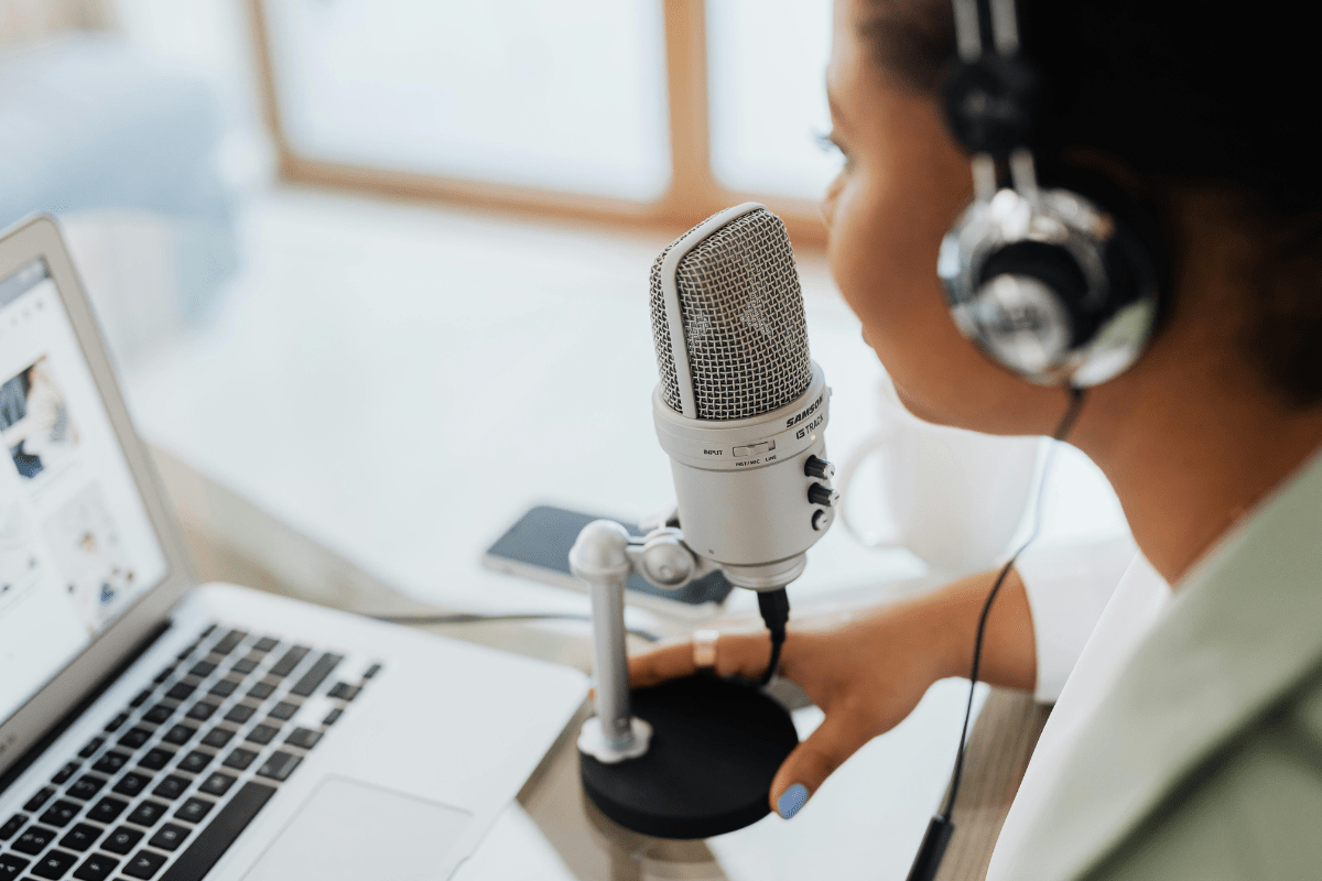 Start Offering Voiceover Artists Services - Online Side Hustles from Home A Woman Wearing Headphone While Speaking In to a Microphone Illustrating Online Side Hustles from Home