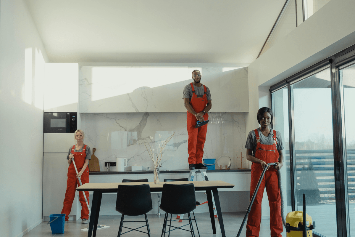 Three cleaners Can Be Seen Standing in a Kitchen With Cleaning Equipment Illustrating How to Start a Move out Cleaning Business