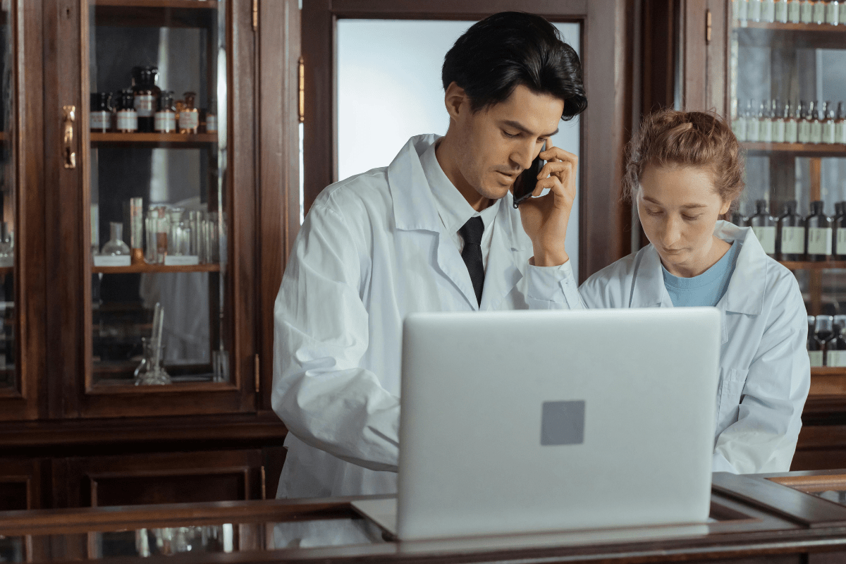 Two Pharmacist Wearing White Coats Seeing Something on a Laptop Illustrating Pharmacist Side Hustle