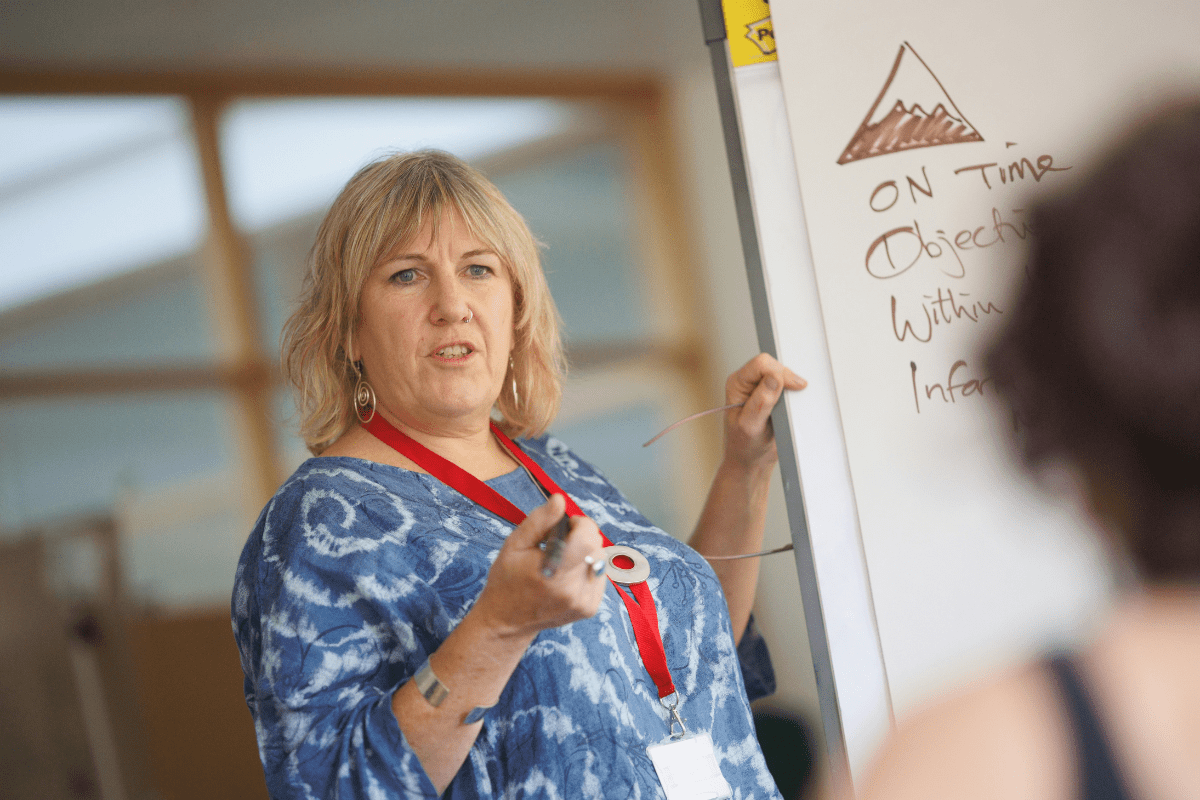 A Woman Teaching Standing beside a White Board Illustrating Pharmacist Side Hustle 