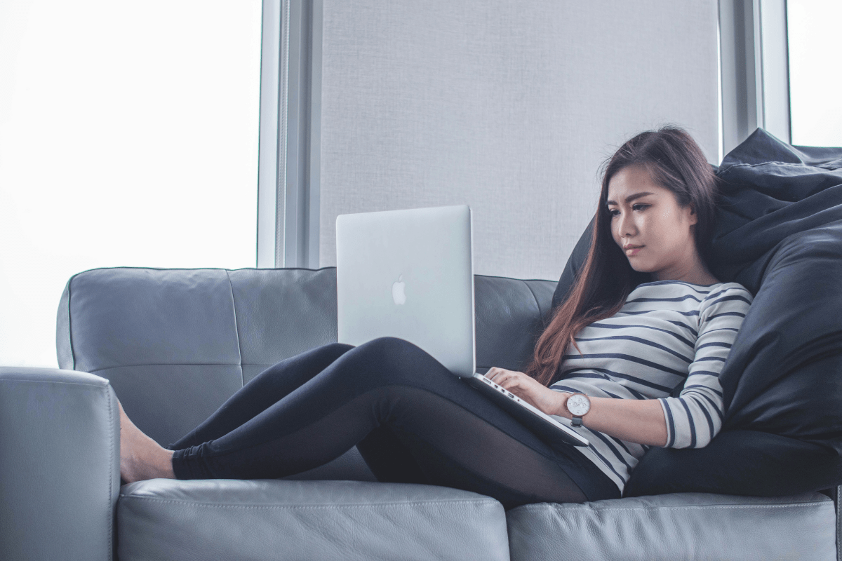 A Woman Is Seen Sitting on a Couch with Laptop in Lap Writing a Blog Post Illustrating Business Ideas for Nurses 
