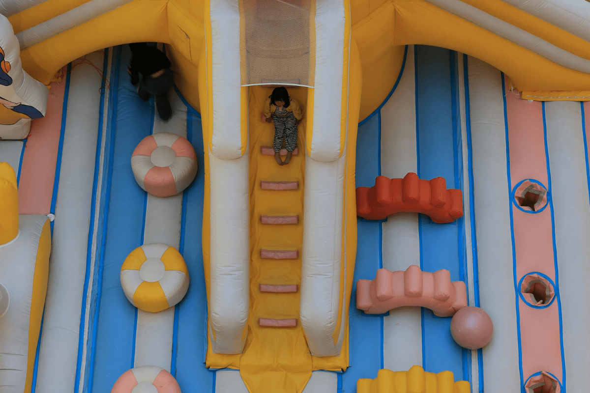 How Profitable is a Bounce House Business? - How to Start a Bounce House Business A Child Can Be Seen Sliding Down on a Bounce House Illustrating How to Start a Bounce House Business