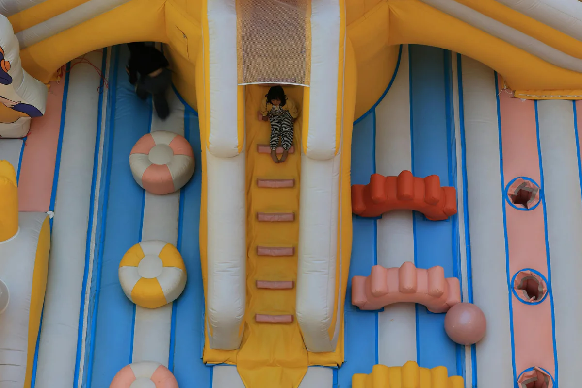 A Child Can Be Seen Sliding Down on a Bounce House Illustrating How to Start a Bounce House Business