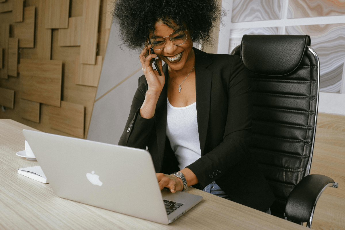 A Woman is Working on Laptop and Talking on Phone while Freelancing Illustrating How to Make $100 a Day