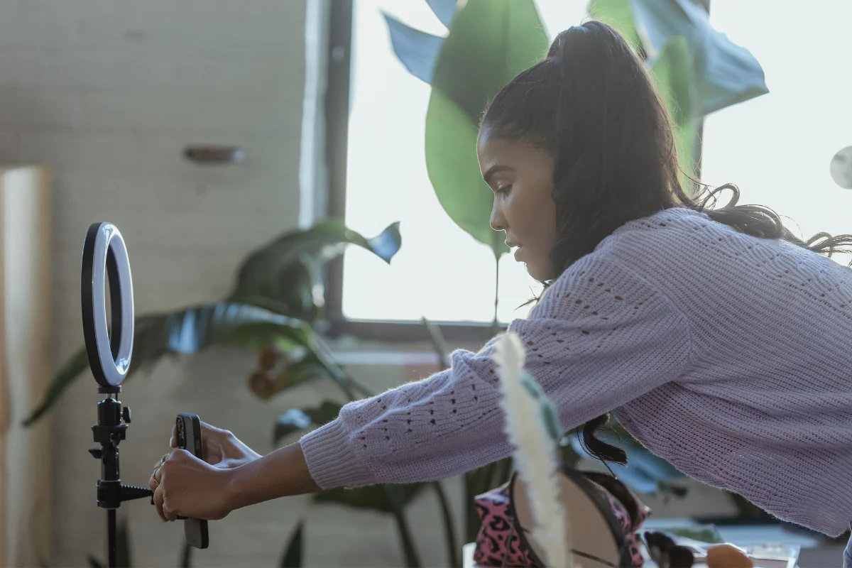 Create Content - AI Side Hustles A Woman is Fixing Her Phone In Front of a Ring Light Illustrating Creating Content and Earning Money by Using AI Side Hustles