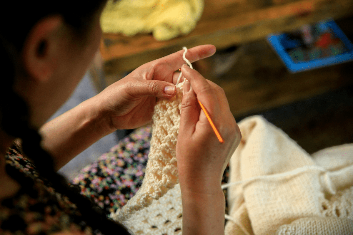 Start an Etsy Shop to Sell Handmade Items - Side Hustles for Introverts A Woman is Seen Crocheting Illustrating Selling Handmade Items as Best Side Hustles for Introverts