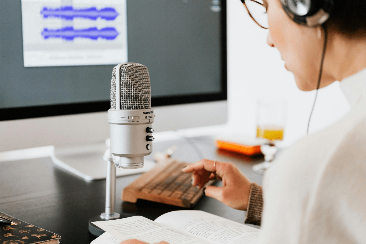 Offer Voice Over Services for Narrations - Passive Income for College Students A Female Is Sitting in front of A Mic and a Computer Screen While Recording Something Illustrating Passive Income for College Students
